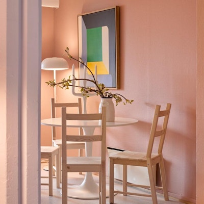 En stue med stoler, bord, blomst og et bilde